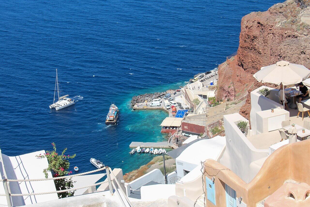 Coastal view of Santorini, Greece with white houses on cliffs overlooking the deep blue Aegean Sea and small boats below